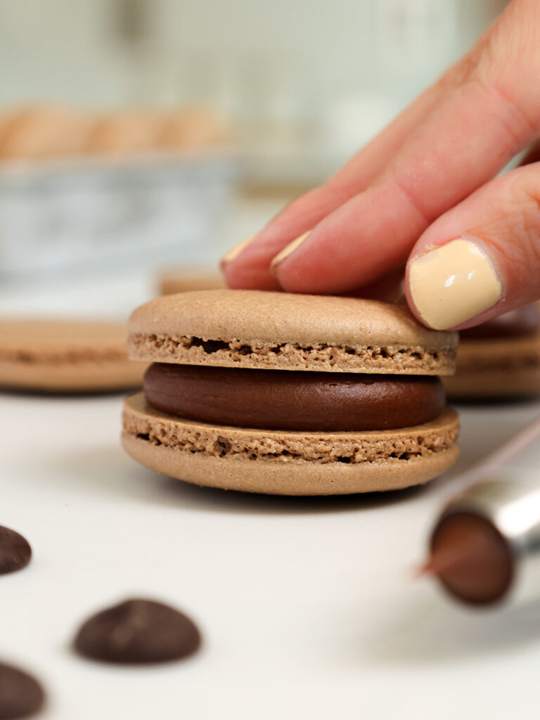 image of a french chocolate macaron being filled with a semi sweet chocolate ganache