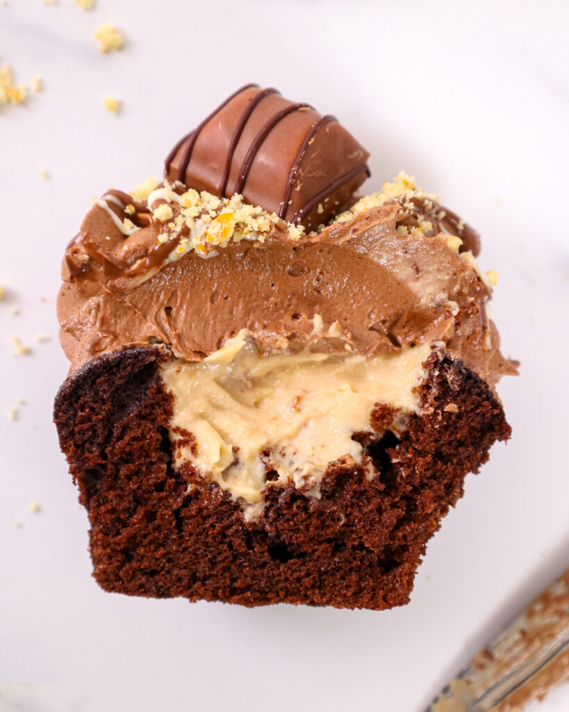image of a Kinder Bueno cupcake that's been cut open to show it's hazelnut mousse filling and chocolate hazelnut buttercream