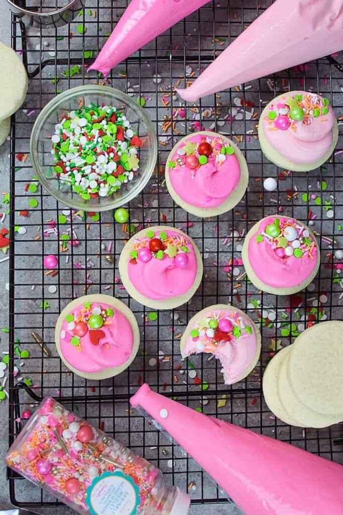 overhead shot of buttercream cookies decorated with pink frosting and sprinkles