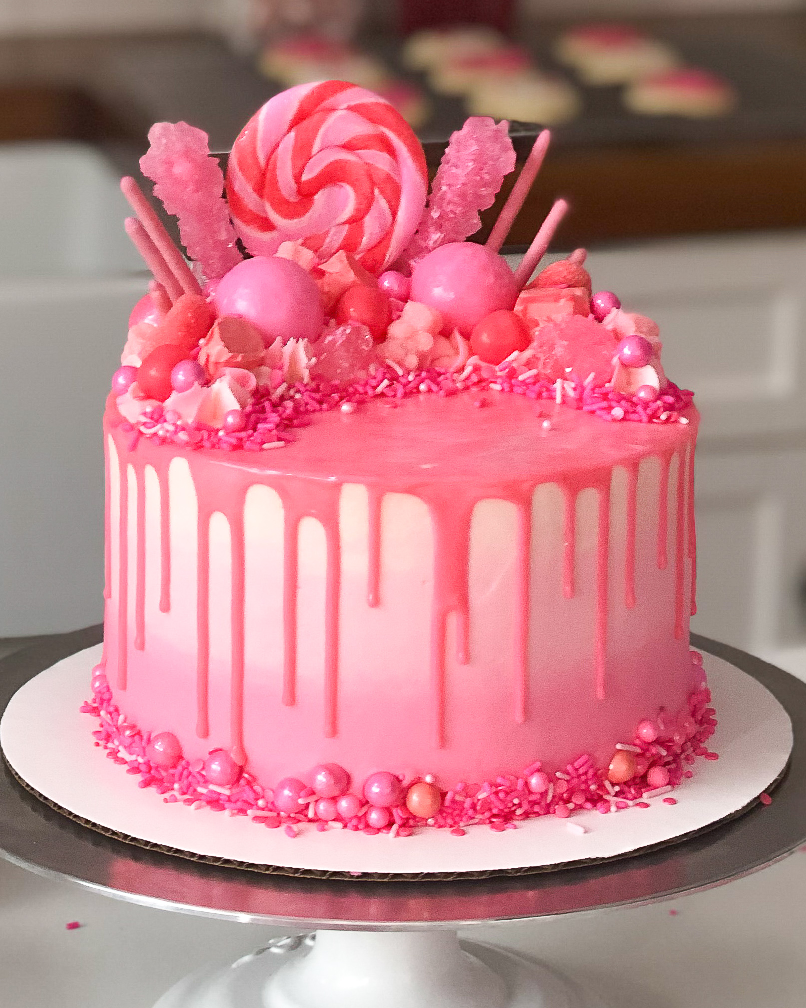 image of pretty pink drip cake decorated with candy for girls birthday party