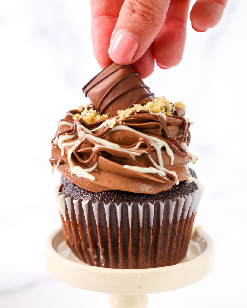 image of a mini kinder bueno bar being pressed on top of a Kinder Bueno cupcake