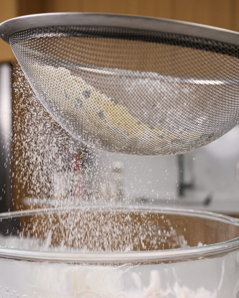 image of dry ingredients being sifted into meringue to make macaron batter