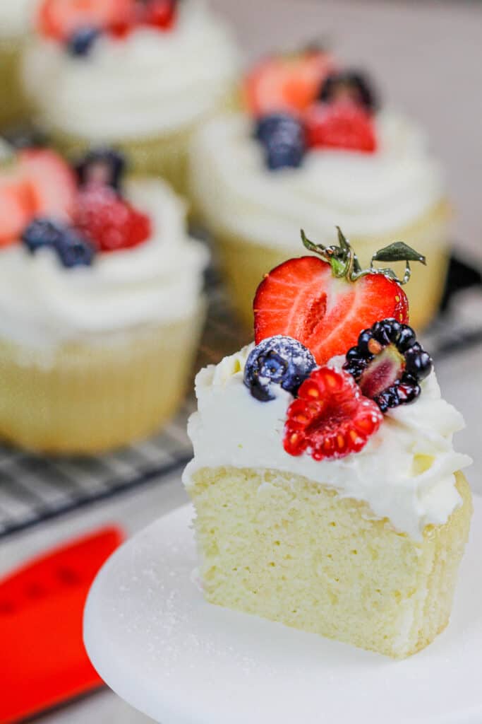 image of a cupcake that's been cut into and topped with whipped cream frosting and fresh fruit