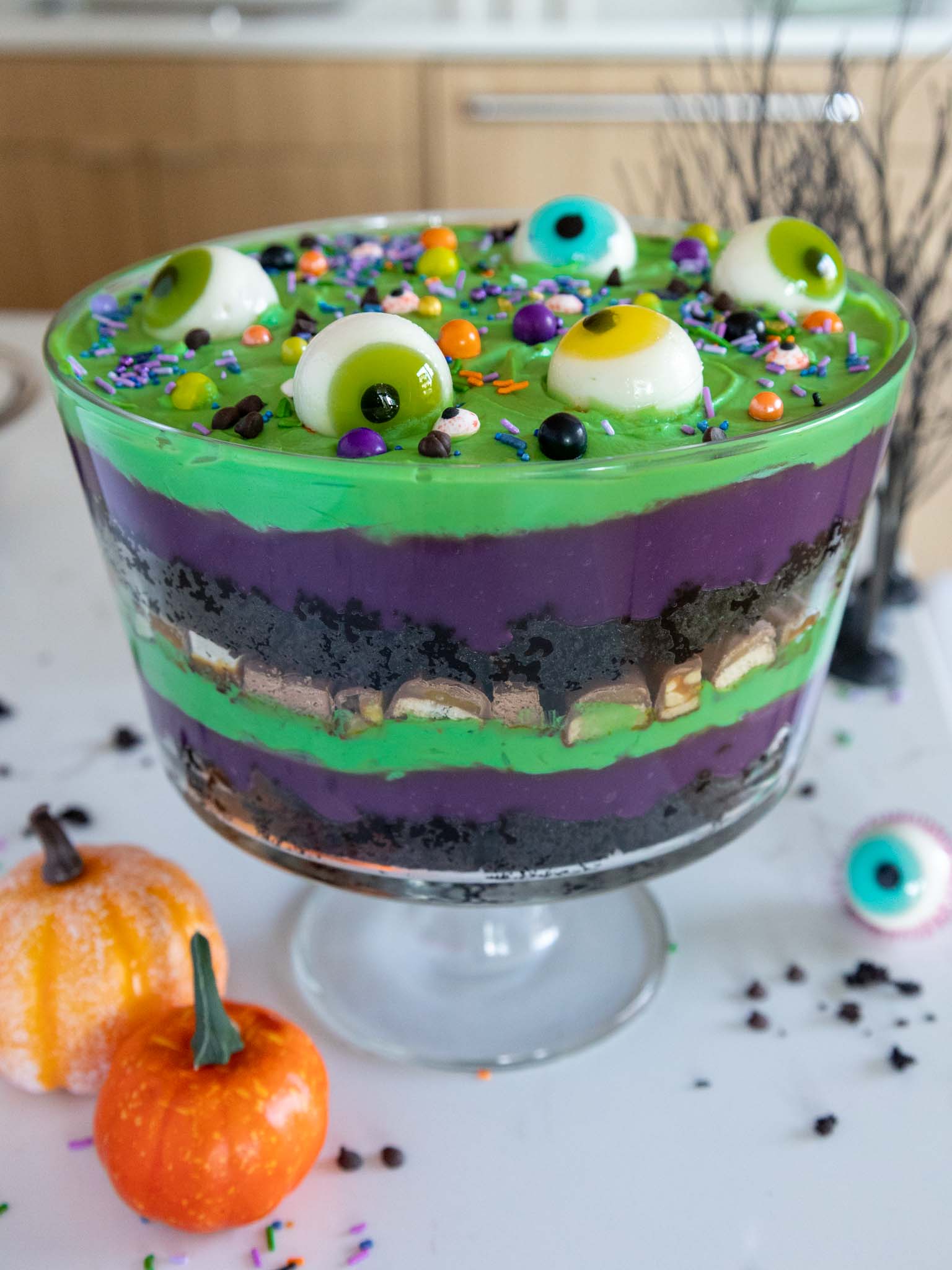 image of a halloween trifle made with purple and green pudding and whipped cream and decorated with gummy eyeballs and halloween sprinkles