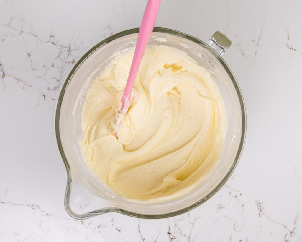 image of white chocolate buttercream that's been mixed in a large glass mixing bowl